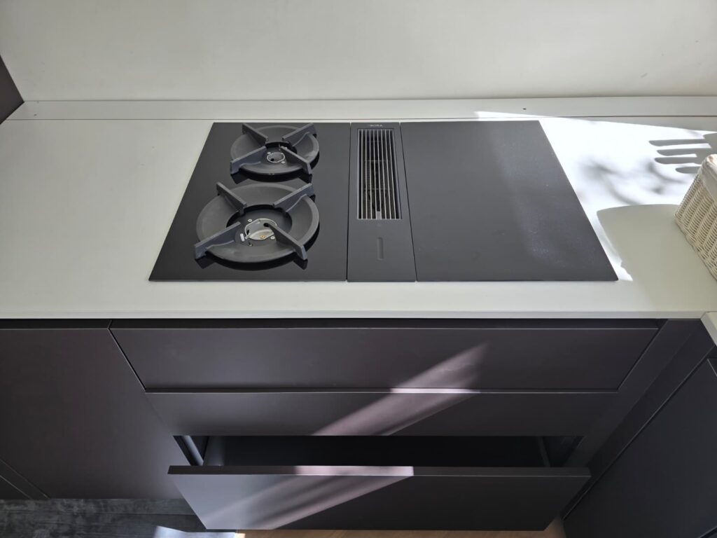 Kitchen hob with integrated extractor above bespoke dark drawers