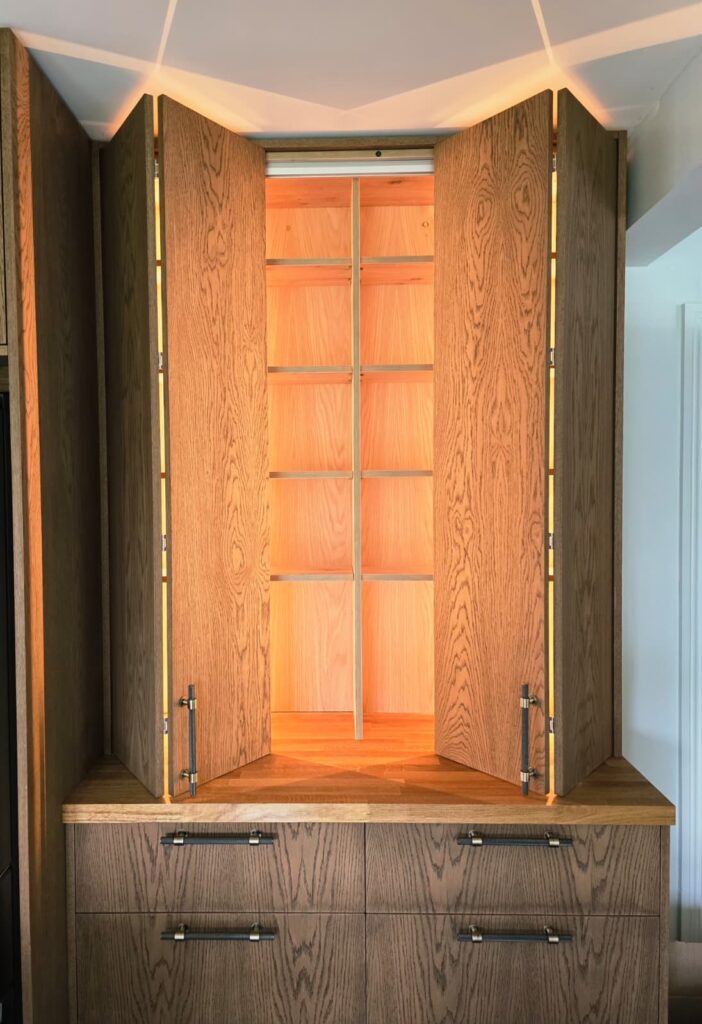 Handmade oak-veneered unit with dark Jacobean finish in Trim, Co. Meath: open illuminated cupboards